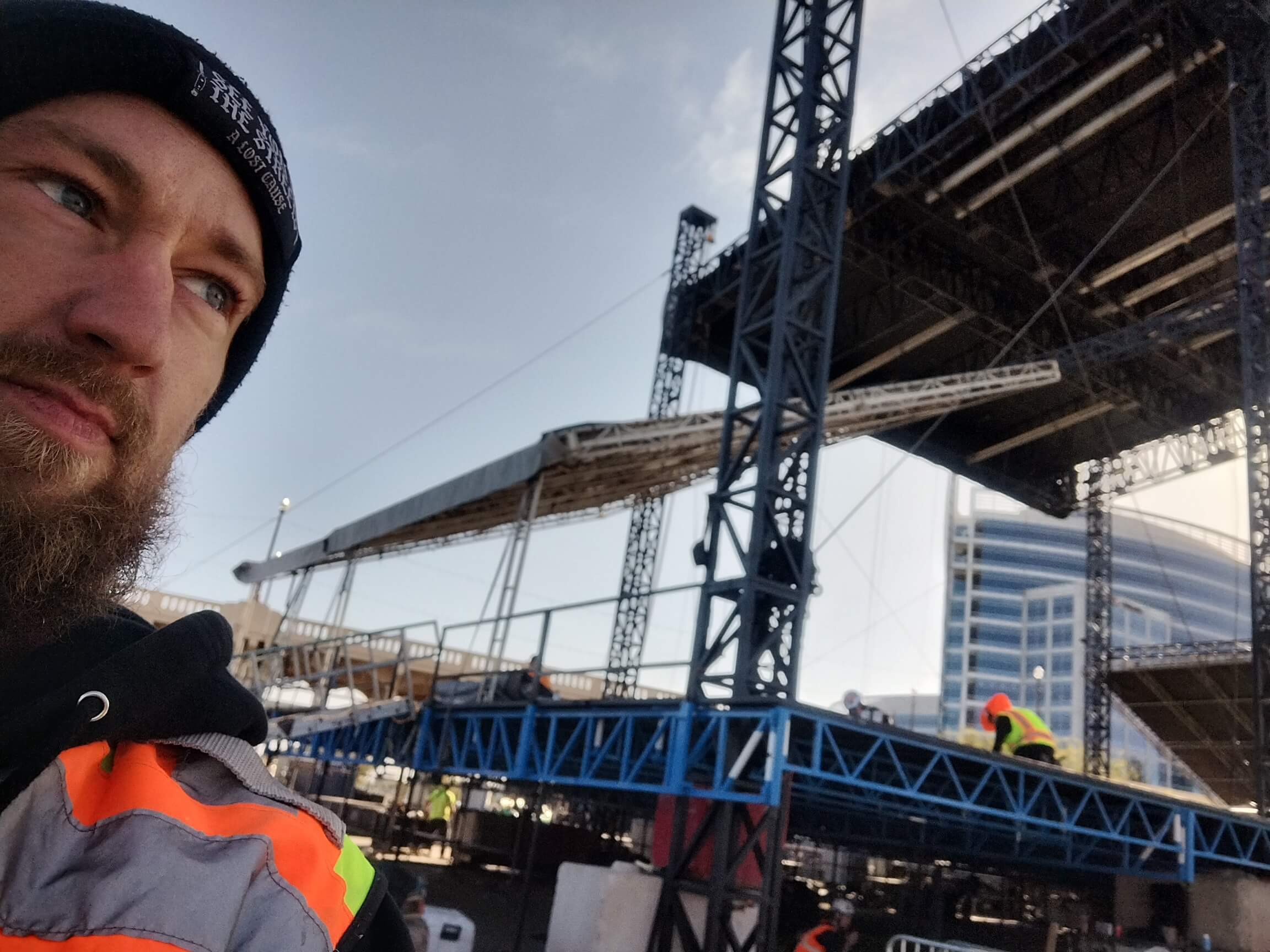 Aaron Bowman in high-vis gear in front of a large outdoor stage truss during festival load-in